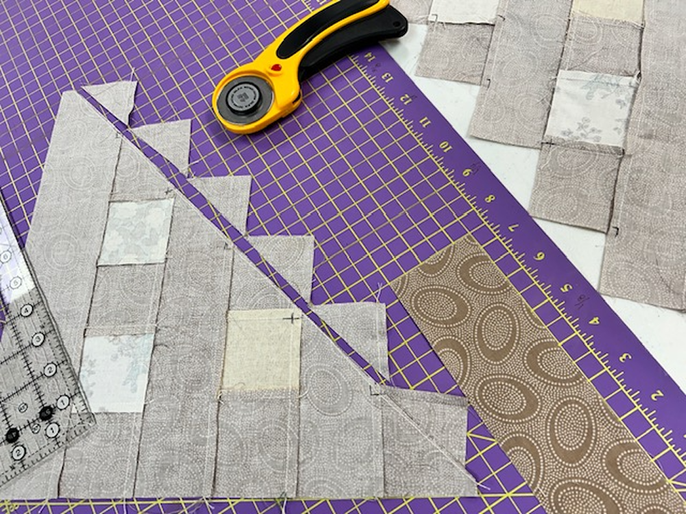 Quilted fabric with a rotary cutter and ruler on a purple cutting mat